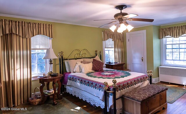 bedroom featuring wood-type flooring, radiator, crown molding, and ceiling fan