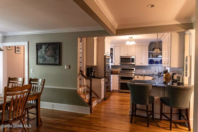 kitchen featuring stainless steel appliances, white cabinets, dark hardwood / wood-style floors, and decorative light fixtures