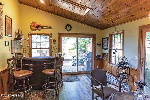 bar featuring vaulted ceiling, wood walls, wooden ceiling, and hardwood / wood-style floors