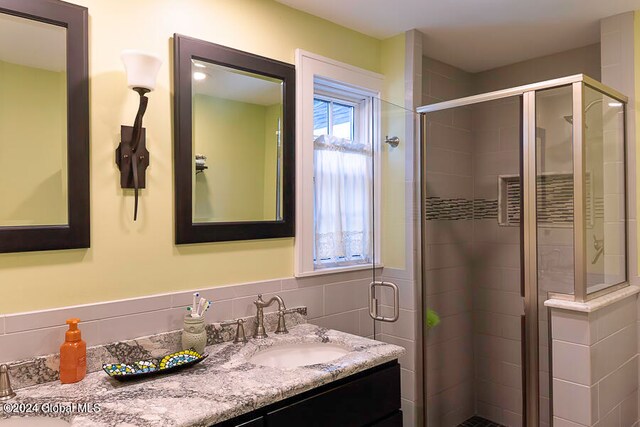 bathroom featuring tile walls, a shower with shower door, and vanity