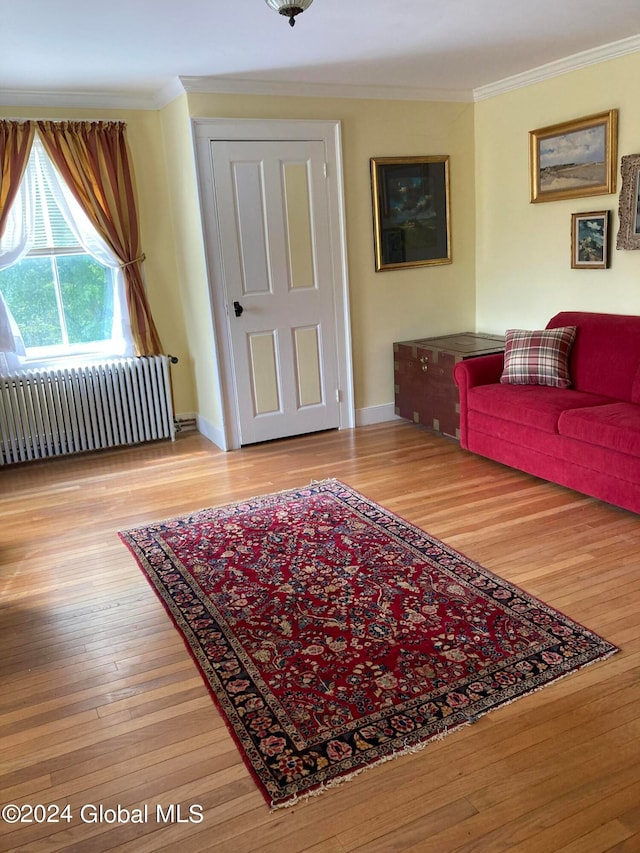 living room with hardwood / wood-style flooring, crown molding, and radiator