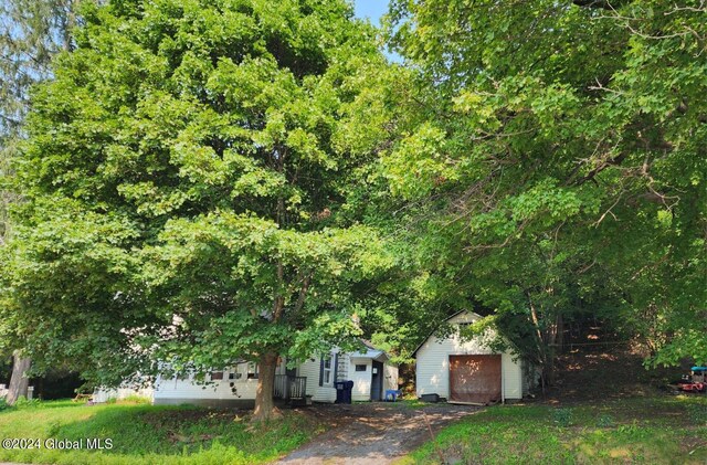 view of property hidden behind natural elements featuring a garage and an outdoor structure