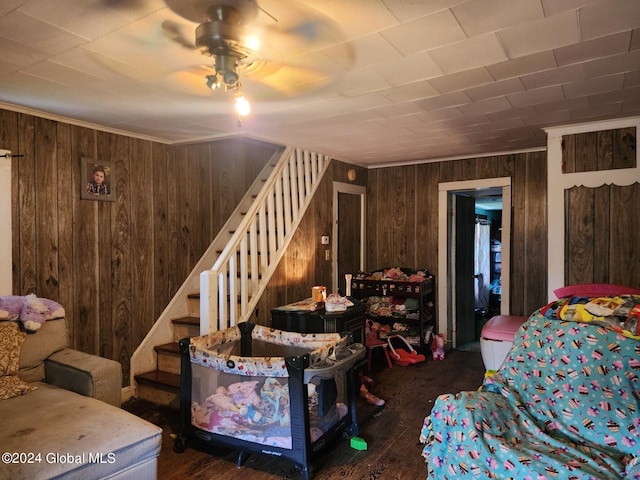 bedroom featuring ceiling fan, wooden walls, and hardwood / wood-style flooring