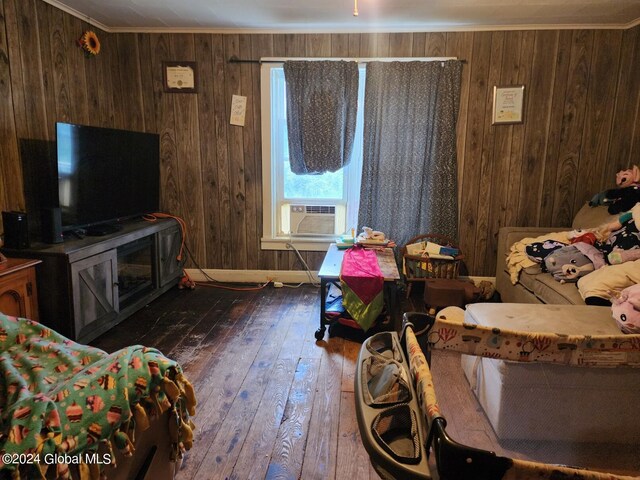 living room featuring wood walls, dark hardwood / wood-style floors, ornamental molding, and cooling unit