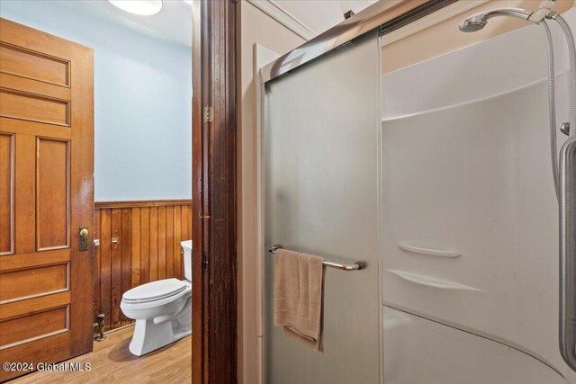 bathroom featuring hardwood / wood-style floors, toilet, an enclosed shower, and wood walls