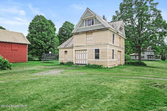 back of property featuring a lawn and a trampoline