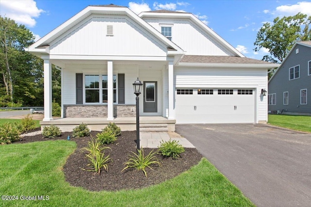 craftsman inspired home featuring a garage, a front lawn, and covered porch