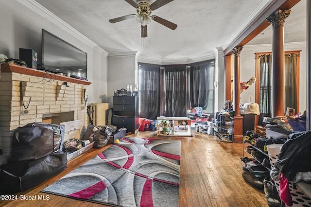 living area featuring radiator, hardwood / wood-style flooring, ceiling fan, crown molding, and ornate columns