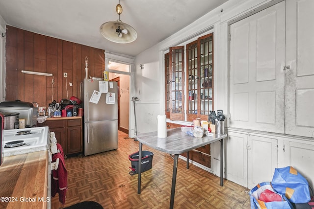 kitchen featuring wood walls, white range with gas cooktop, light countertops, and freestanding refrigerator