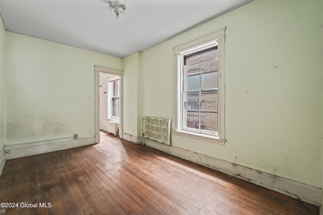 spare room featuring radiator and hardwood / wood-style floors