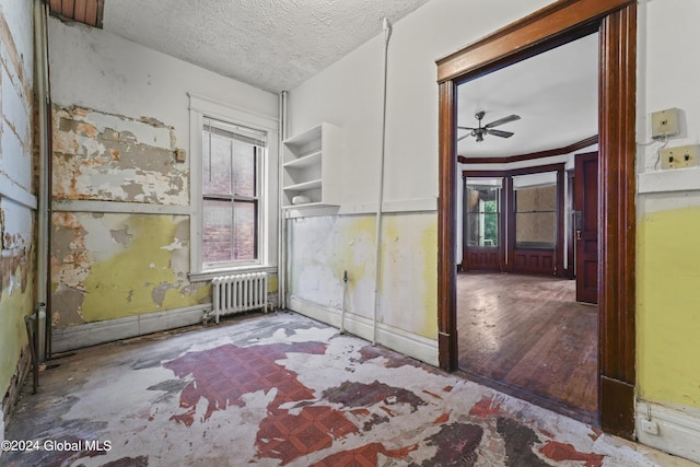 empty room with radiator, ceiling fan, a textured ceiling, and wood finished floors