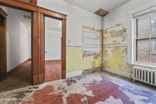 empty room with radiator and a textured ceiling