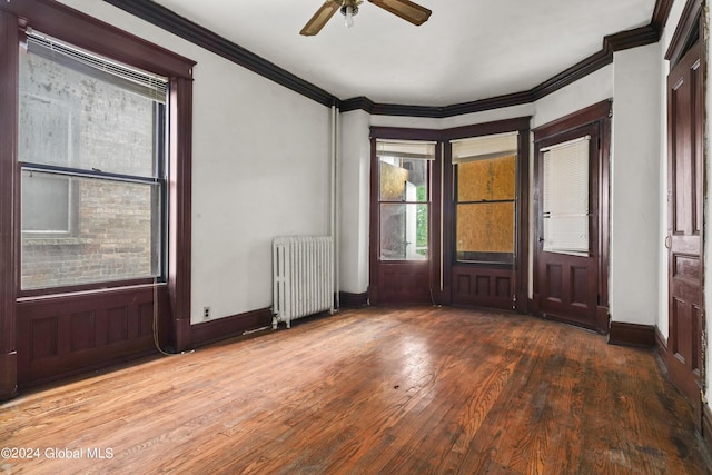 foyer with radiator heating unit, crown molding, baseboards, and wood finished floors