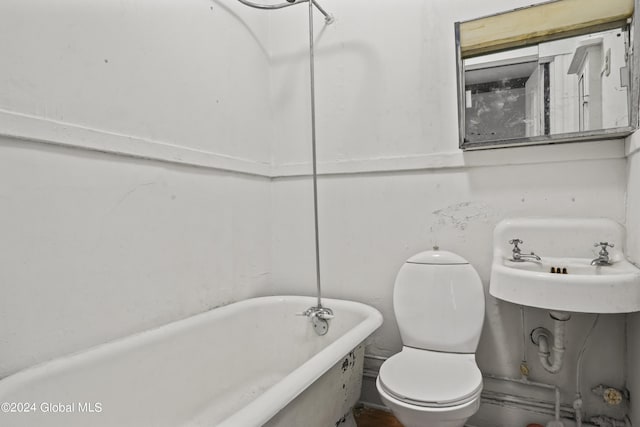 full bathroom featuring a freestanding tub, a sink, and toilet