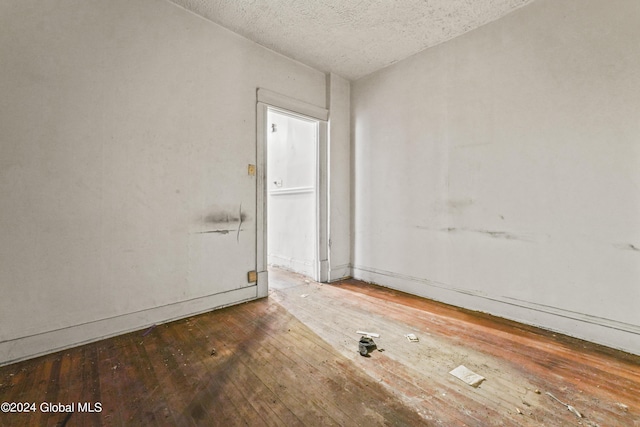 unfurnished room featuring wood-type flooring and a textured ceiling