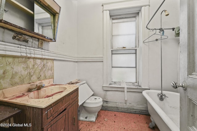 full bath featuring toilet, a healthy amount of sunlight, a freestanding bath, and vanity