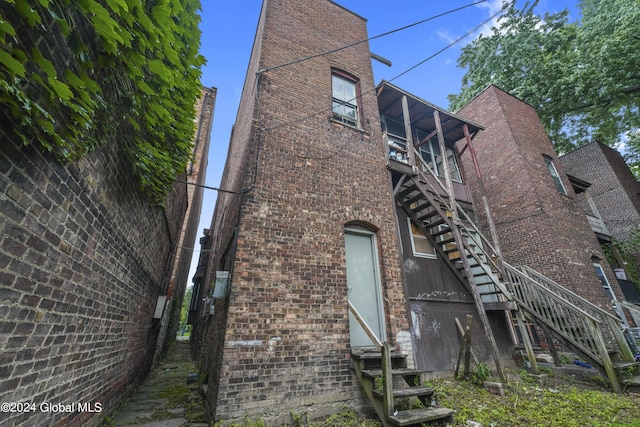 rear view of house with entry steps, brick siding, and stairway