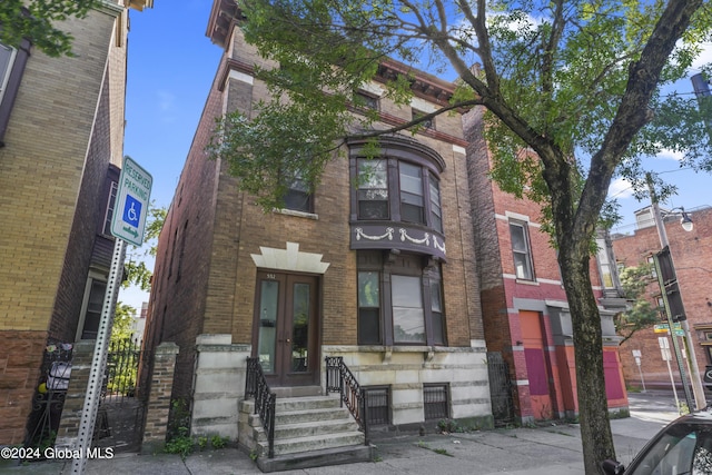 view of front facade with entry steps, french doors, and brick siding