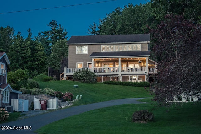 rear view of property featuring central air condition unit and a lawn