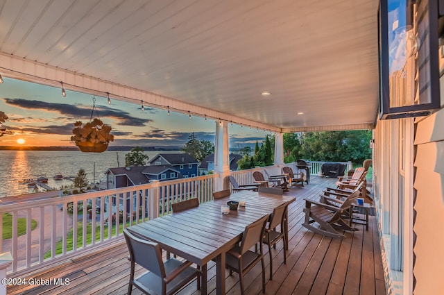 deck at dusk featuring a water view