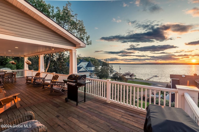 deck at dusk featuring a water view and grilling area