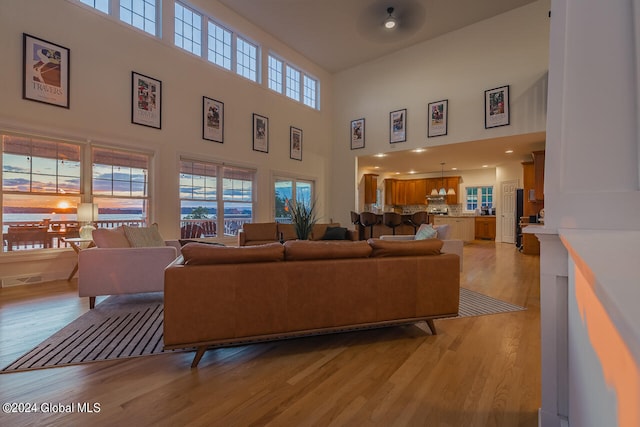 living room featuring light hardwood / wood-style floors, a wealth of natural light, and a towering ceiling