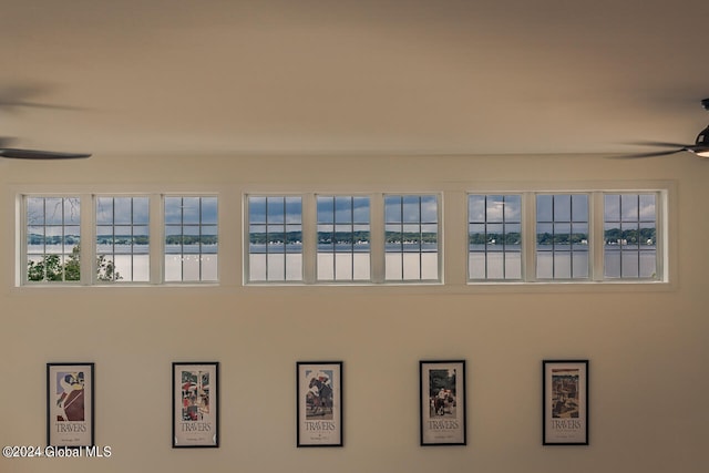 interior details featuring ceiling fan and a water view