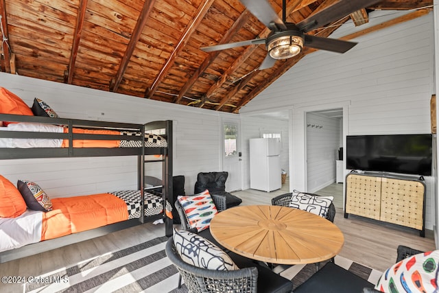 bedroom featuring white refrigerator, wood ceiling, light hardwood / wood-style floors, wooden walls, and beamed ceiling