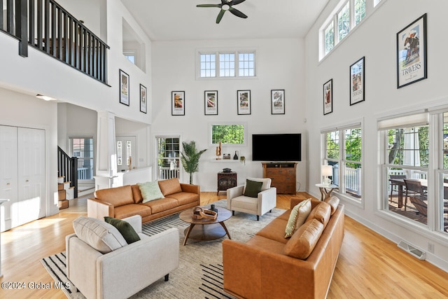 living room with ceiling fan, light hardwood / wood-style flooring, a high ceiling, and ornate columns