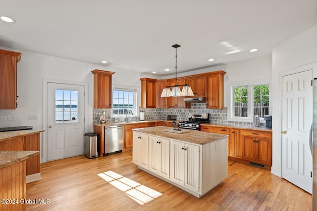 kitchen with hanging light fixtures, sink, a kitchen island, light hardwood / wood-style flooring, and stainless steel appliances