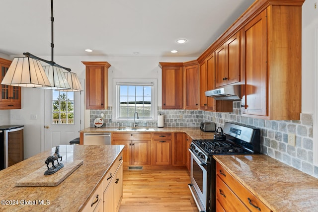 kitchen featuring stainless steel appliances, tasteful backsplash, light hardwood / wood-style floors, sink, and hanging light fixtures