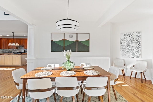 dining room featuring beamed ceiling and light hardwood / wood-style flooring