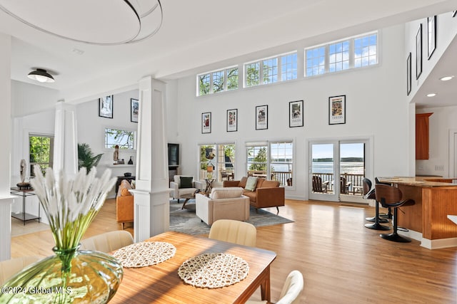 interior space with light hardwood / wood-style floors, a towering ceiling, and ornate columns