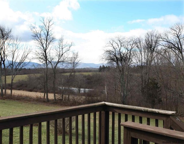 wooden deck with a lawn, a mountain view, and a rural view