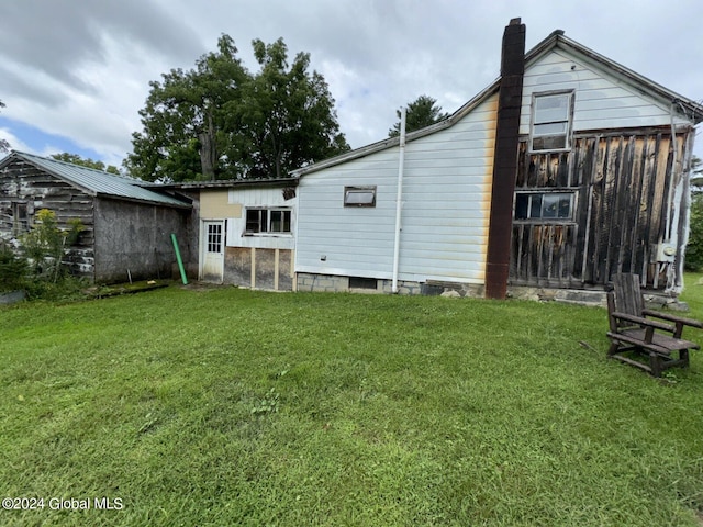 back of property with an outdoor structure and a lawn