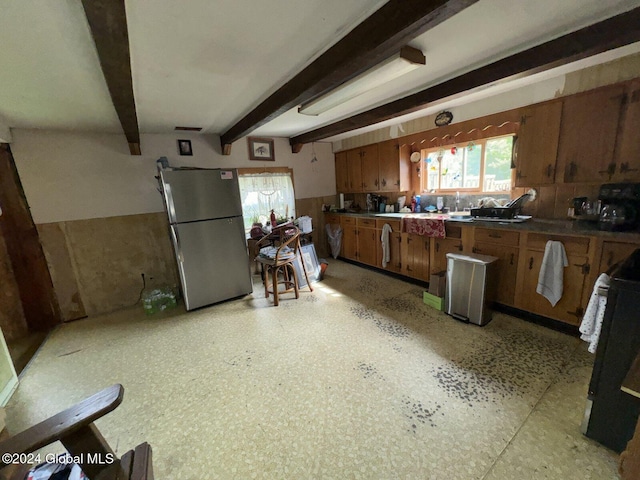 kitchen with beamed ceiling, stove, and stainless steel refrigerator