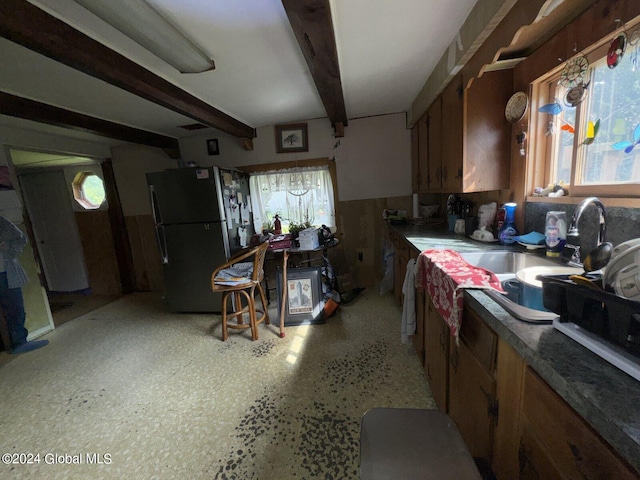 kitchen featuring a wealth of natural light, beamed ceiling, and black refrigerator