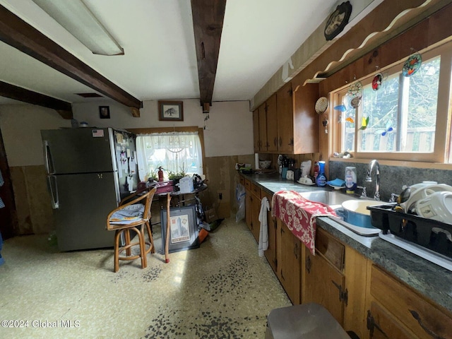 kitchen with black fridge, beamed ceiling, sink, and a wealth of natural light