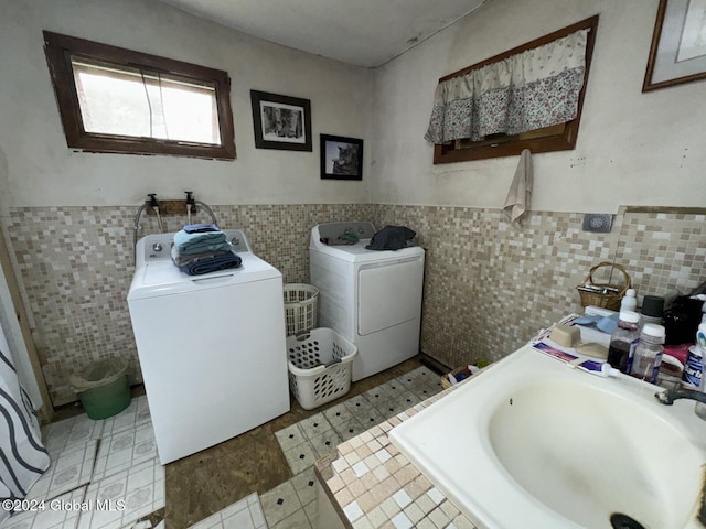 washroom featuring light tile patterned floors, washer and dryer, sink, and tile walls