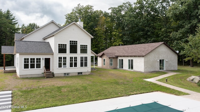 back of property with a covered pool and a lawn