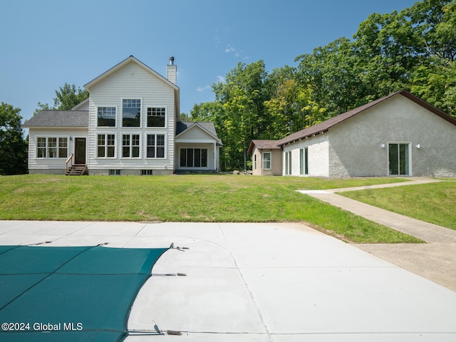 back of house with a yard and a covered pool