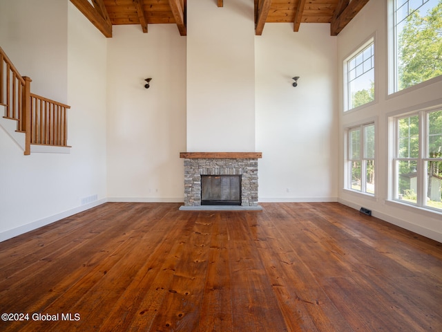 unfurnished living room featuring dark wood-type flooring, high vaulted ceiling, beamed ceiling, and a wealth of natural light