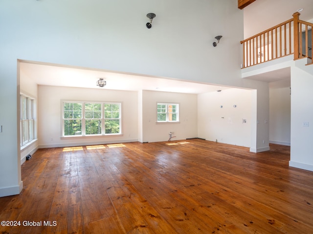 unfurnished living room featuring hardwood / wood-style flooring and a towering ceiling