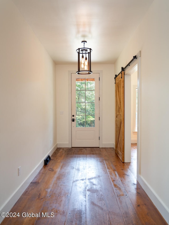 doorway to outside featuring a notable chandelier, hardwood / wood-style flooring, and a barn door