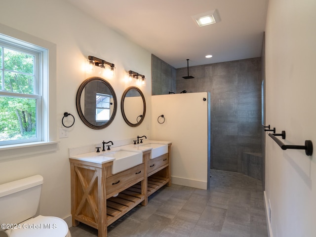 bathroom with toilet, vanity, and a tile shower