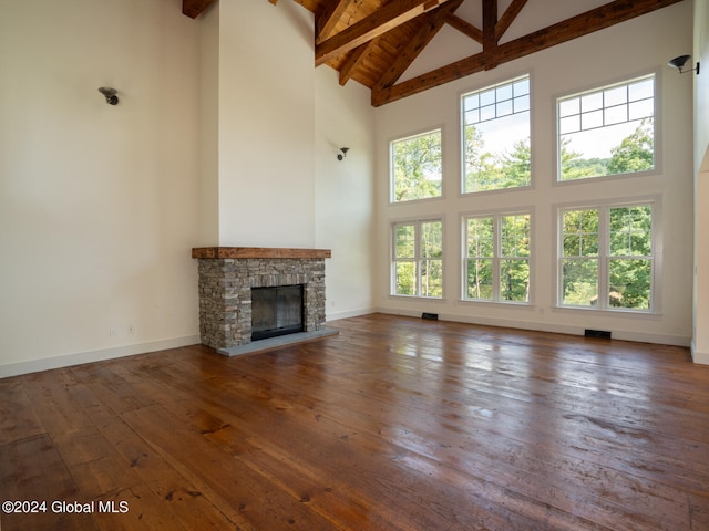 unfurnished living room featuring beamed ceiling, dark hardwood / wood-style floors, high vaulted ceiling, and a fireplace