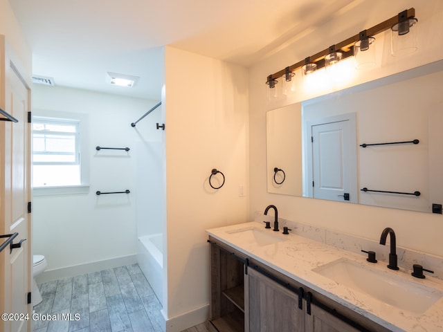 full bathroom featuring toilet, vanity, wood-type flooring, and washtub / shower combination