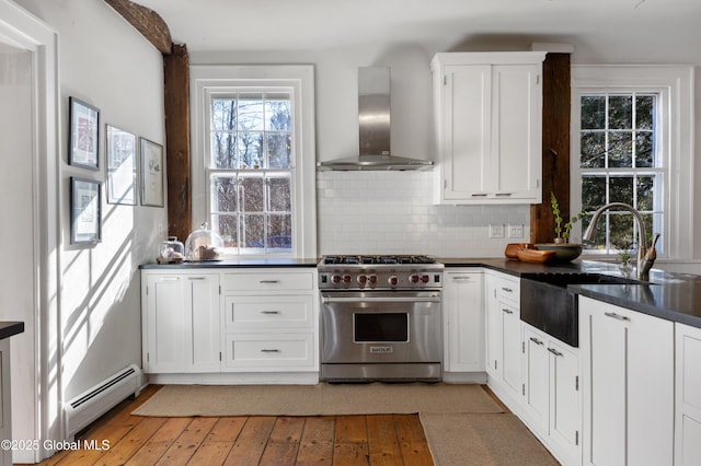 kitchen featuring wall chimney exhaust hood, dark countertops, premium range, and a baseboard radiator