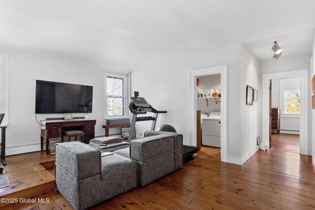 living area featuring a baseboard radiator, wood-type flooring, a wealth of natural light, and washer and clothes dryer