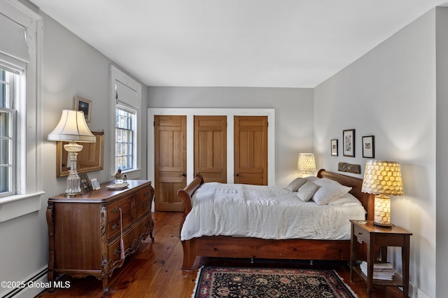 bedroom with a baseboard heating unit and wood-type flooring